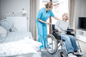 NDIS support worker providing in-home care to elderly woman in wheelchair, disability support services Australia